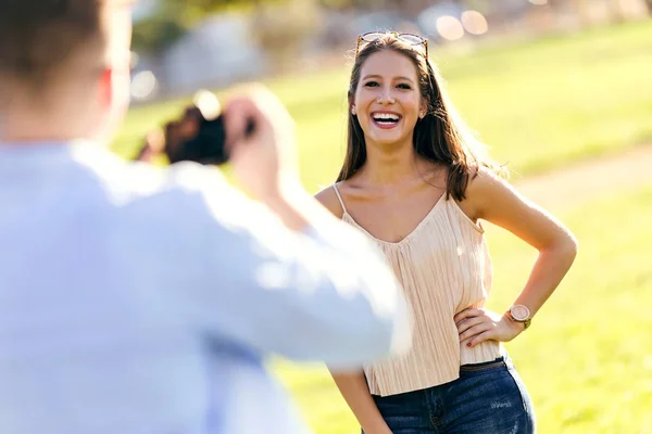 Handsome young man taking photo of his girlfriend in the park. — Stock Photo, Image