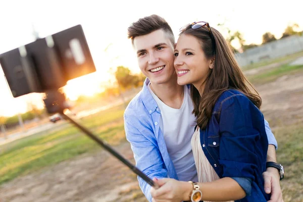 Belo jovem casal tirando uma selfie no parque . — Fotografia de Stock