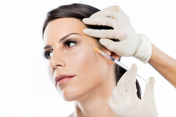 Beautiful young woman getting botox cosmetic injection in her face over white background. — Stock Photo, Image
