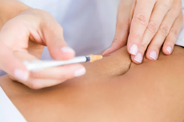 Chirurg maken van injectie in het vrouwelijk lichaam. Liposuctie concept. — Stockfoto