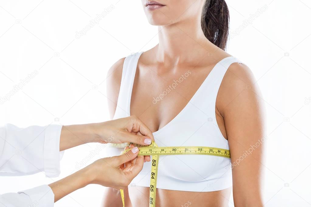 Doctor with measure tape measuring the size of the patient's breast.