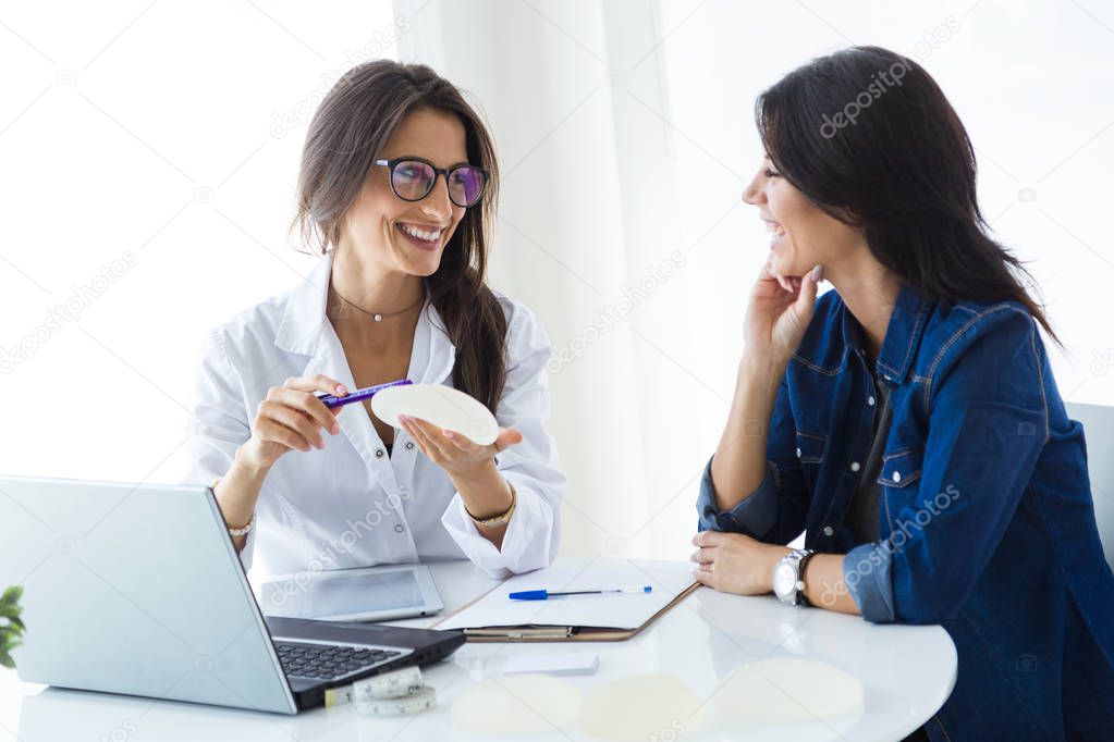 Doctor and her patient choosing mammary prosthesis in the office