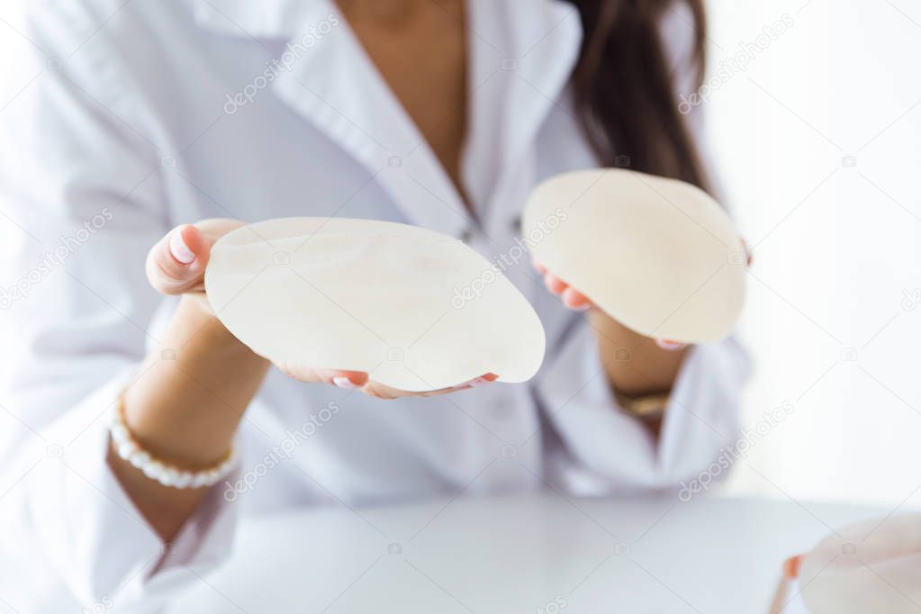 Female doctor choosing mammary prosthesis in the office.