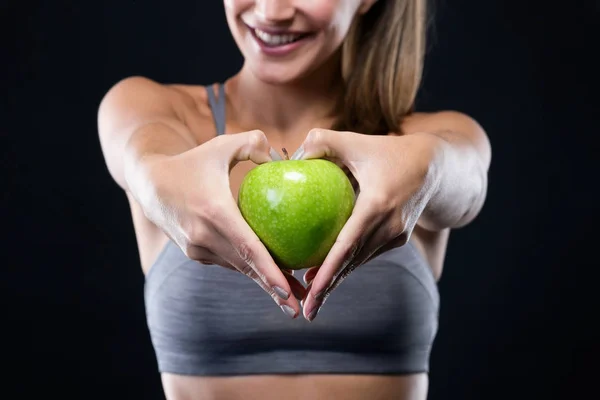 Hermosa joven sosteniendo una manzana sobre fondo negro . — Foto de Stock