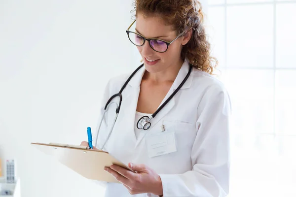 Fiducioso medico donna scrivere informazioni del suo paziente in ufficio . — Foto Stock