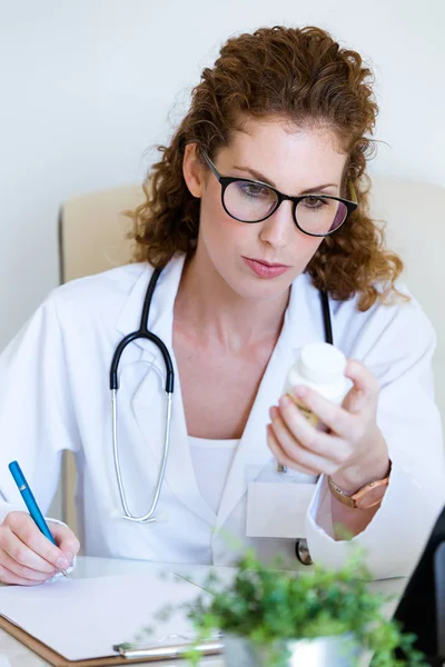 Piękne kobiece farmaceuty, trzymając słoik pigułki w ręce w biurze. — Zdjęcie stockowe