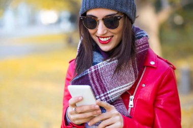 Sonbaharda cep telefonu kullanan güzel genç kadın.
