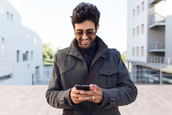 Jovem moderno usando seu telefone celular na rua . — Fotografia de Stock