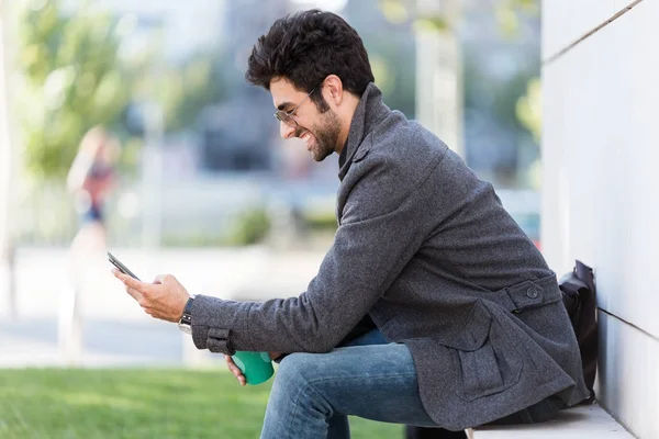 Jovem moderno usando seu telefone celular na rua . — Fotografia de Stock