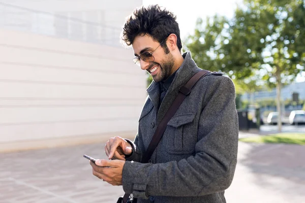 Jeune homme moderne utilisant son téléphone portable dans la rue . — Photo