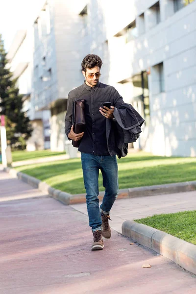 Jovem moderno usando seu telefone celular na rua . — Fotografia de Stock