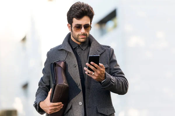 Jeune homme moderne utilisant son téléphone portable dans la rue . — Photo