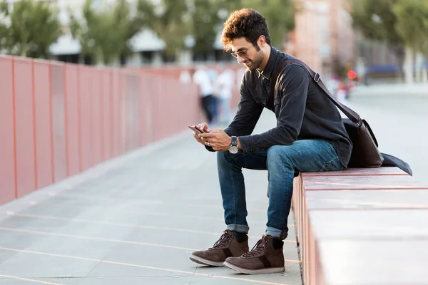 Moderne jonge man met zijn mobiele telefoon in de straat. — Stockfoto