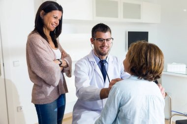 Anne ile kızı stetoskop ile çocuk doktoru tarafından muayene ediliyor.