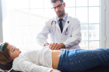 Kız ofiste çocuk doktoru tarafından muayene ediliyor.