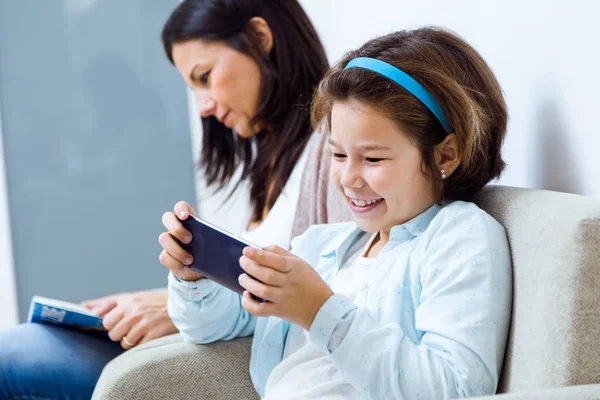 Mother and daughter using mobile phone in the waiting room of the doctor. — Stock Photo, Image