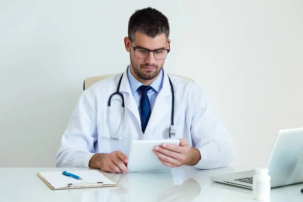 Уверенный врач-мужчина, использующий свой цифровой планшет в офисе . — стоковое фото