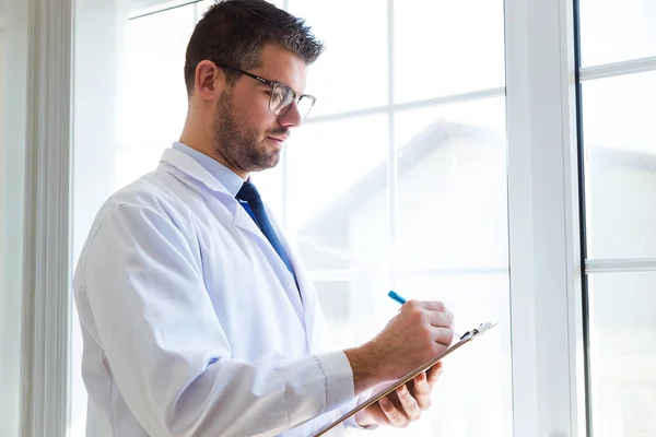 Självsäker manliga läkare skriva information av hans patient på kontoret. — Stockfoto