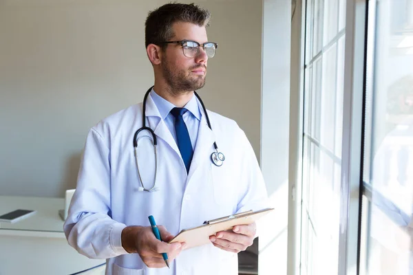 Confident male doctor looking sideways in the office.