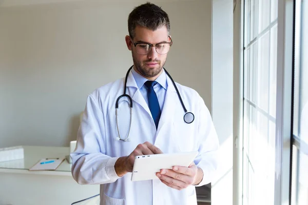 Självsäker manliga läkare använder sin digitala surfplatta på kontoret. — Stockfoto