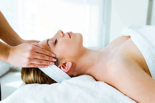 Vacker ung kvinna med spa ansiktsbehandling massage i skönhetssalongen. — Stockfoto