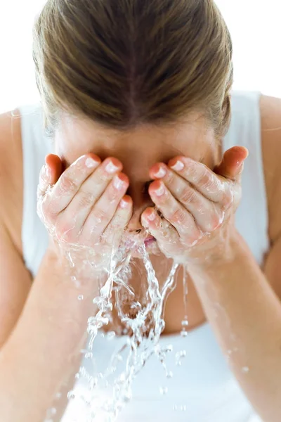 Gyönyörű fiatal nő mossa arcát fröccsenő víz egy otthoni fürdőszobában. — Stock Fotó