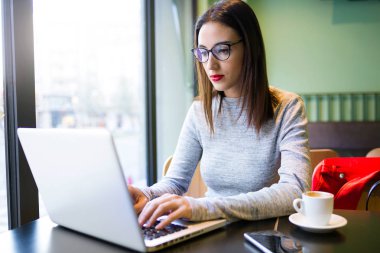 Kahve dükkanında onu laptop kullanan güzel genç kadın.