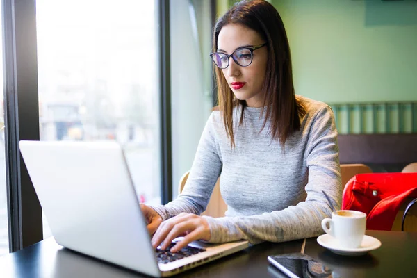 Kahve dükkanında onu laptop kullanan güzel genç kadın.