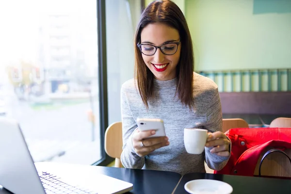 Schöne junge Frau mit Handy beim Kaffeetrinken im Café. — Stockfoto
