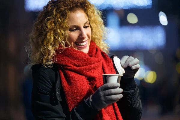 Schöne junge Frau, die nachts auf der Straße Kaffee trinkt. — Stockfoto