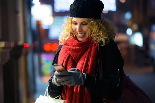 Belle jeune femme utilisant son téléphone portable dans la rue la nuit . — Photo