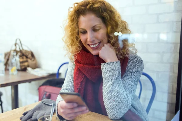Красивая молодая женщина использует свой мобильный телефон в кафе-магазине . — стоковое фото
