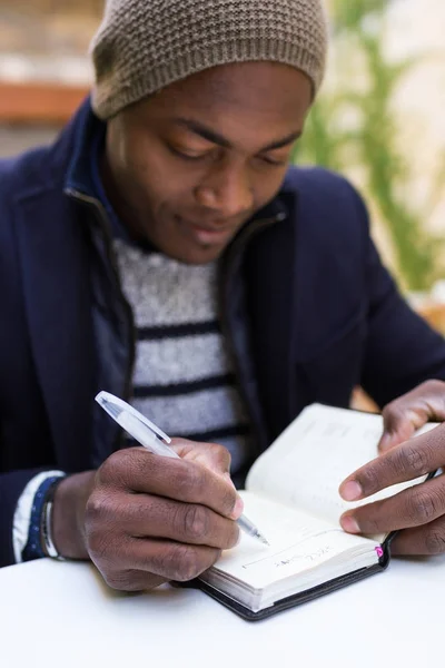 Όμορφος νεαρός άνδρας γράφει σε ένα σημειωματάριο. — Φωτογραφία Αρχείου