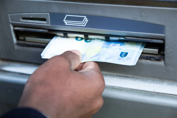 Close up of man taking cash from ATM with credit card. — Stock Photo, Image