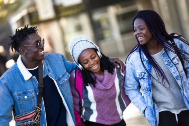 Grup üç arkadaşıyla birlikte yürüyüş ve sokakta gülüyor.