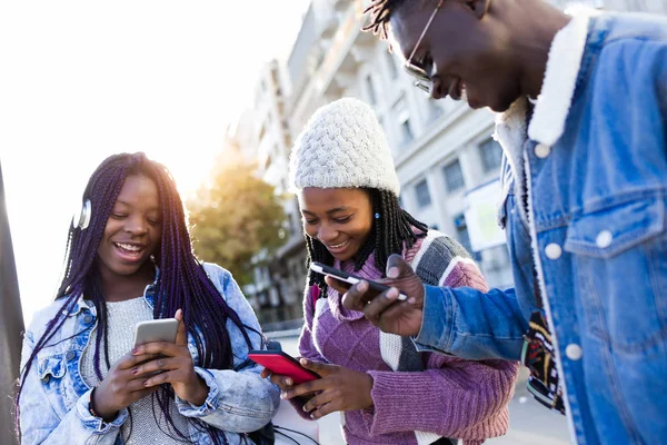 Grupo de tres amigos usando el teléfono móvil en la calle . —  Fotos de Stock