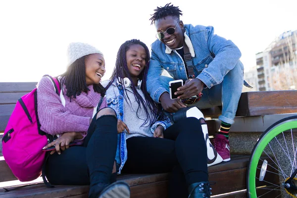 Group of three friends using mobile phone in the street. — Stock Photo, Image