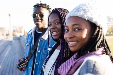 Grup üç arkadaşıyla birlikte sokakta kamera bakıyor.