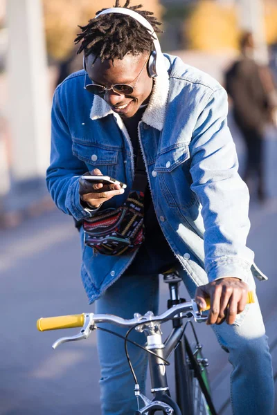 Bello giovanotto che usa il cellulare e la bicicletta a scatto fisso per strada . — Foto Stock