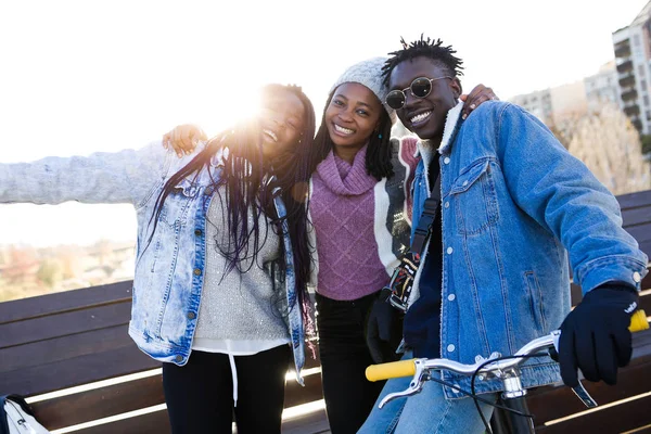 Grup üç arkadaşıyla birlikte sokakta kamera bakıyor.