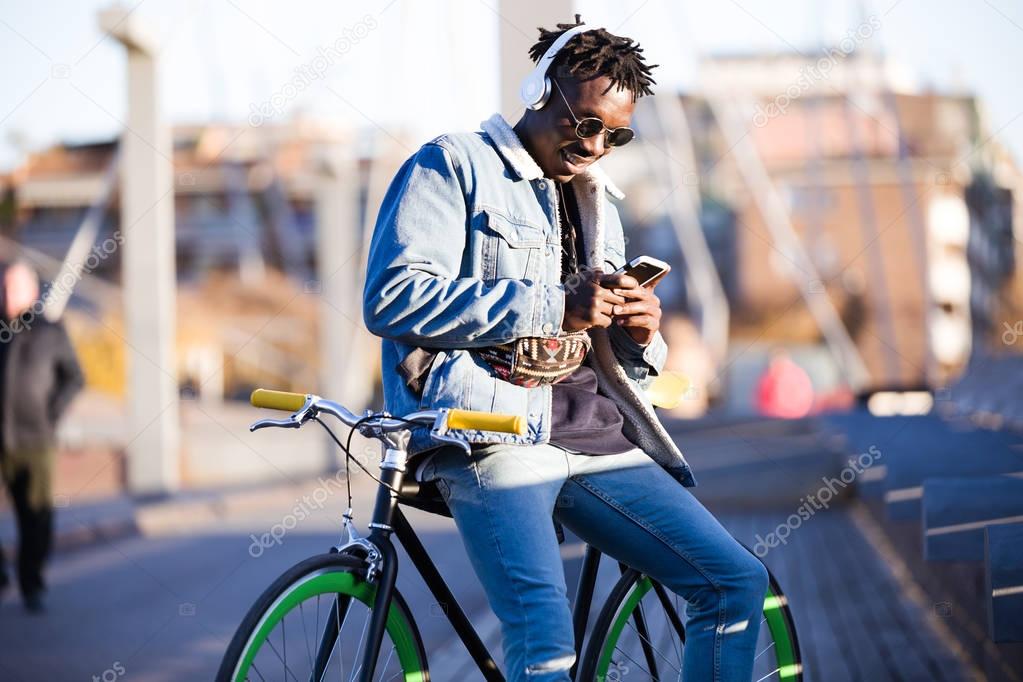 Handsome young man using mobile phone and fixed gear bicycle in the street.