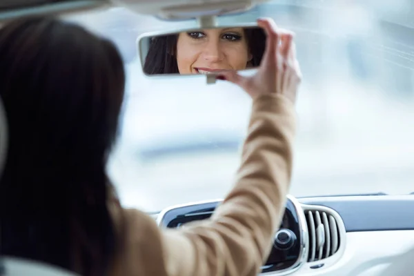 Schöne junge Frau befestigt Rückspiegel des Autos. — Stockfoto