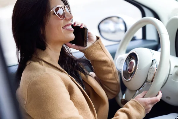 Schöne junge Frau mit ihrem Handy im Auto. — Stockfoto