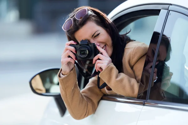 Beautiful young woman taking photos from the car — Stock Photo, Image