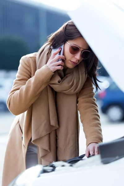 Schöne junge Frau telefoniert mit ihrem Handy um Hilfe für ihr Auto. — Stockfoto