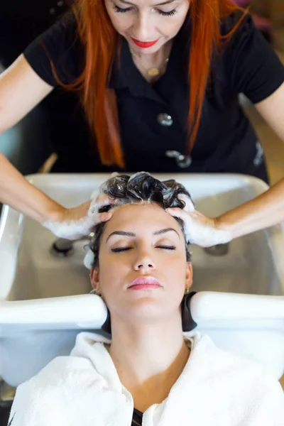 Frumoasa femeie tânără spală părul într-un salon de înfrumusețare . — Fotografie, imagine de stoc