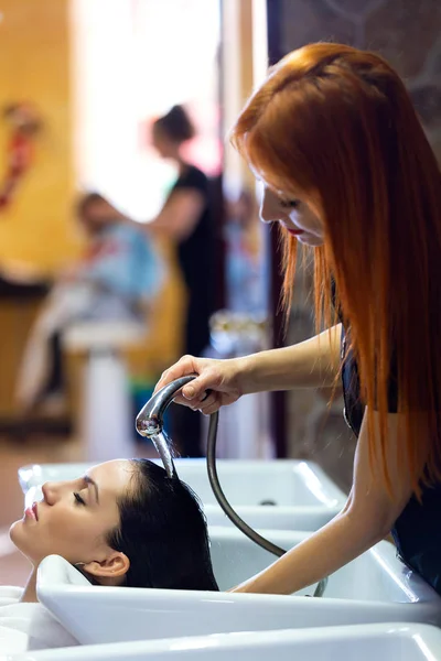 Piękna młoda kobieta myje włosy w salonie piękności. — Zdjęcie stockowe