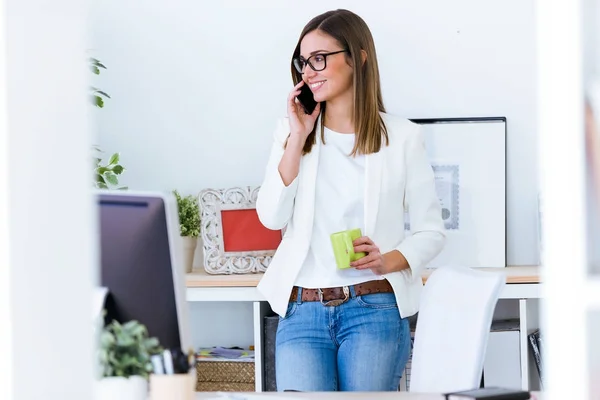 Mujer joven de negocios usando su teléfono móvil en la oficina . —  Fotos de Stock