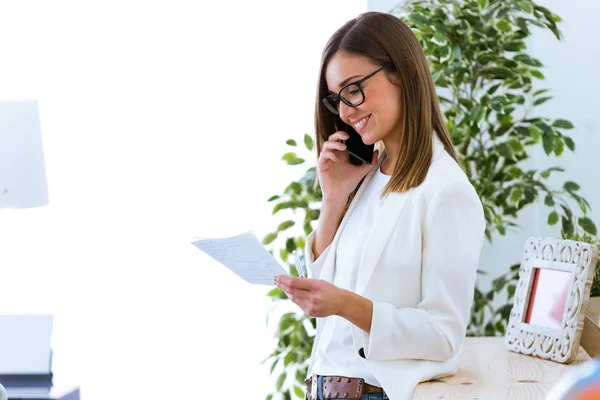 Obchodní mladá žena pomocí její mobilní telefon v kanceláři. — Stock fotografie