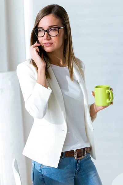 Jonge zakenvrouw met behulp van haar mobiele telefoon in het kantoor. — Stockfoto